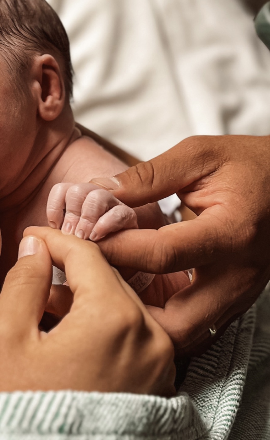 Tiny newborn hand gripping a parent's finger