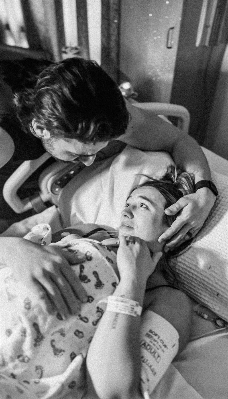 Mother resting as partner gently holds her face after delivery