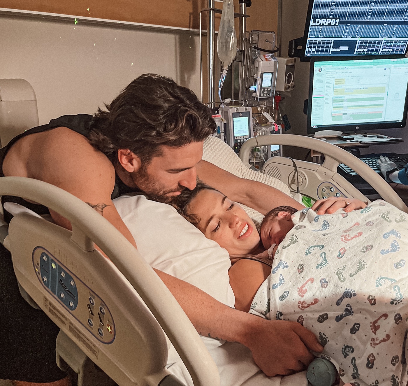 New parents lying together with their newborn in the hospital bed