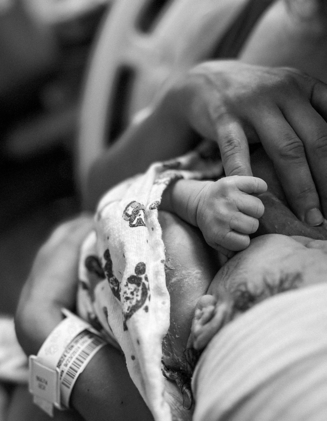 Black and white close-up of a newborn gripping a parent's finger