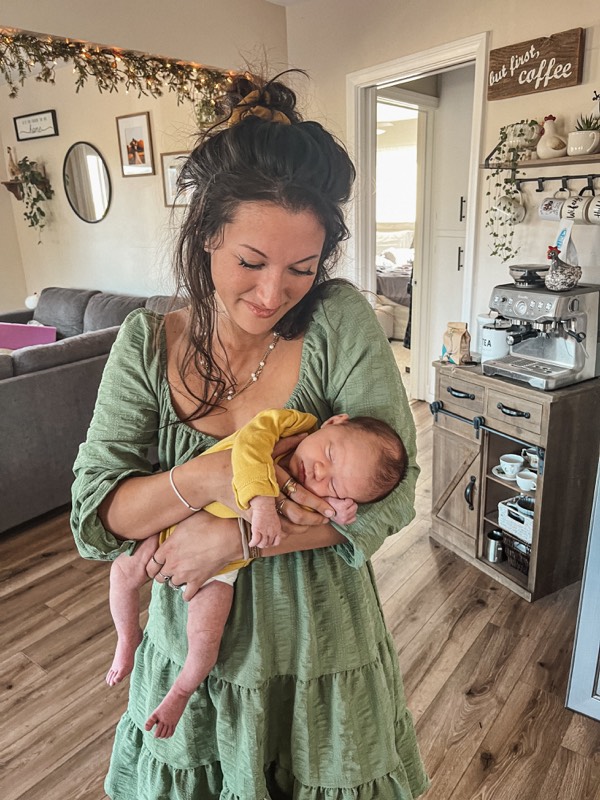 Juliana in a green dress cradling a newborn baby